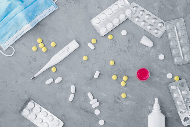 farmaci che alleviano i sintomi di una malattia virale, una maschera medica e un termometro sono sul tavolo, vista dall'alto
 - Foto, immagini