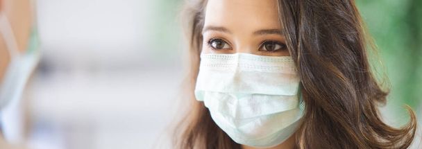 ほこりや感染ウイルスを防ぐために医療用マスクを身に着けている顔の女性を閉じます. - 写真・画像