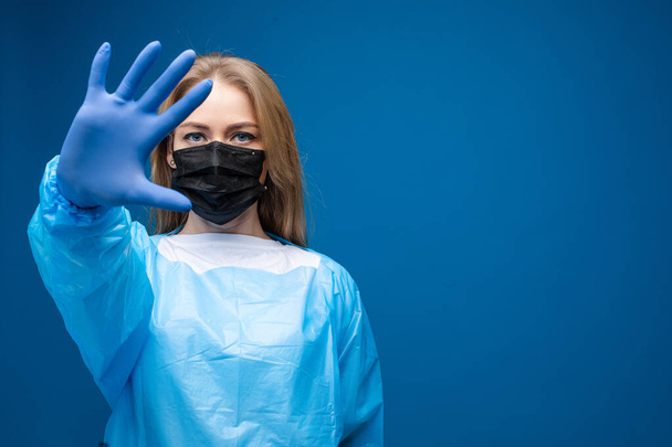 Frau mit Atemschutzmaske zeigt Stoppgeste. Stoppt Viren-Konzept. - Foto, Bild
