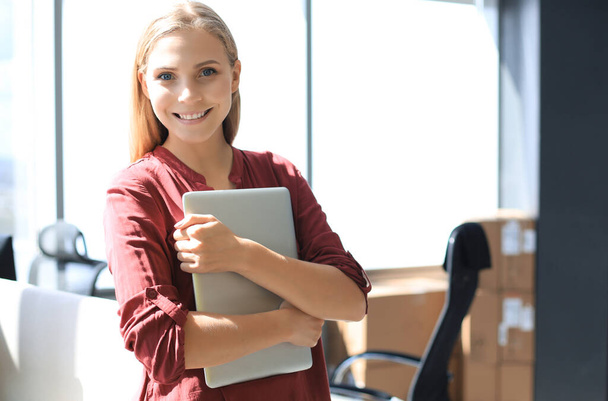 Attractive business woman looking at camera and smiling while standing in the office. - 写真・画像
