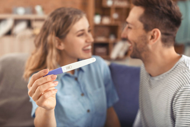 Happy young couple with pregnancy test at home - Foto, afbeelding