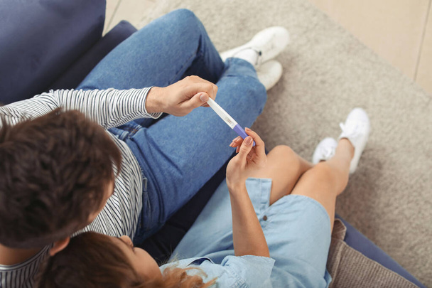 Νεαρό ζευγάρι με τεστ εγκυμοσύνης στο σπίτι, top view - Φωτογραφία, εικόνα