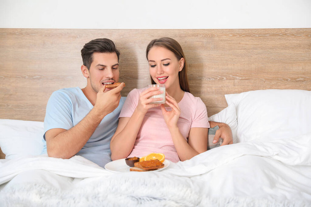 Mañana de pareja joven desayunando en la cama
 - Foto, imagen