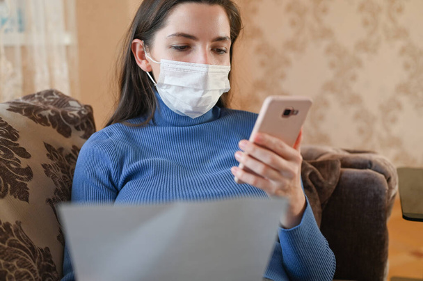 masked girl makes online shopping. Purchasing according to the list in the delivery service close-up. The first signs of coronavirus. - 写真・画像