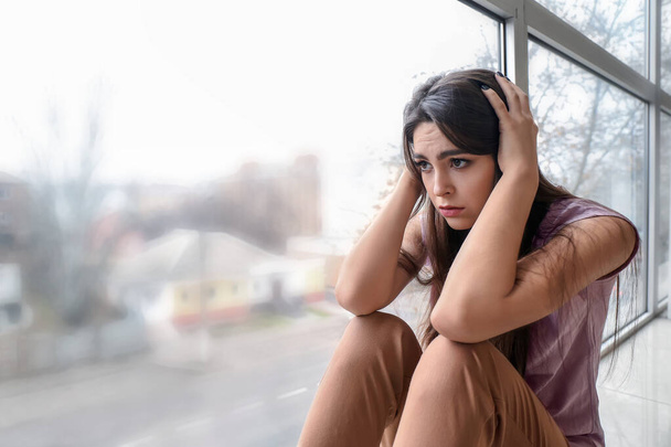 Depressive junge Frau in der Nähe von Fenster zu Hause - Foto, Bild
