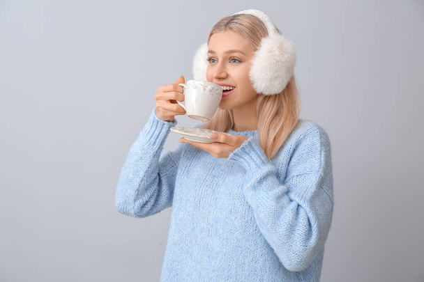 Bella giovane donna con tazza di tè su sfondo grigio - Foto, immagini