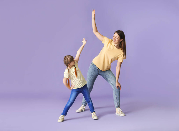 Happy mother and her little daughter dancing against color background - Photo, image