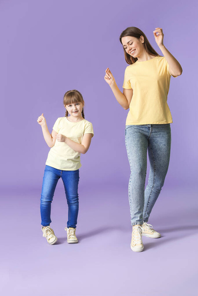glückliche Mutter und ihre kleine Tochter tanzen vor farbigem Hintergrund - Foto, Bild