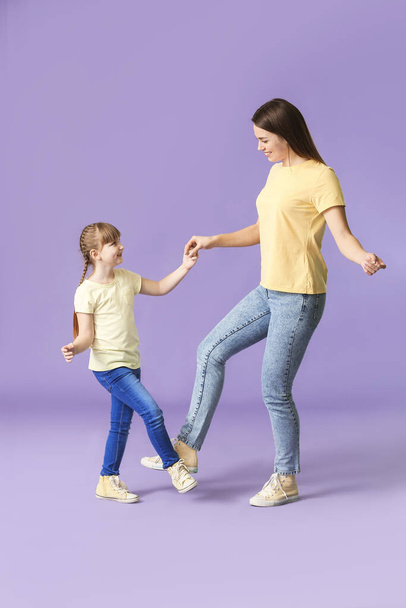 Happy mother and her little daughter dancing against color background - Fotó, kép