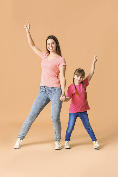 Happy mother and her little daughter dancing against color background - Φωτογραφία, εικόνα