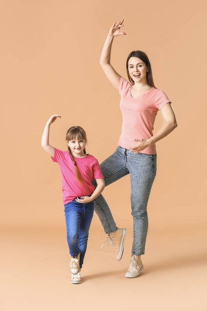 Happy mother and her little daughter dancing against color background - Fotografie, Obrázek