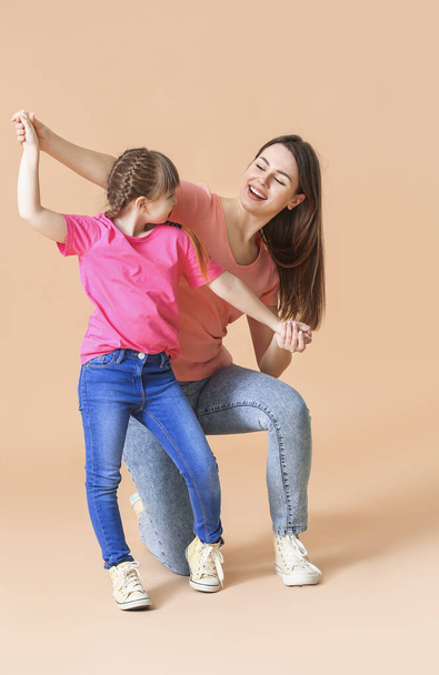 Happy mother and her little daughter dancing against color background - Фото, зображення