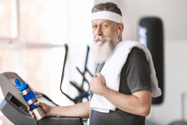Homem idoso desportivo com garrafa de água no ginásio
 - Foto, Imagem