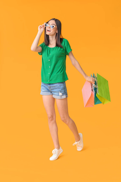 Beautiful young woman with shopping bags on color background - Foto, imagen