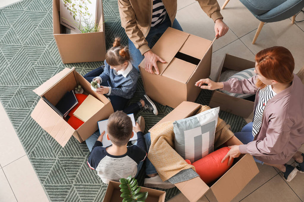 Сім'я розпаковує рухомі коробки у своєму новому будинку, вид зверху
 - Фото, зображення