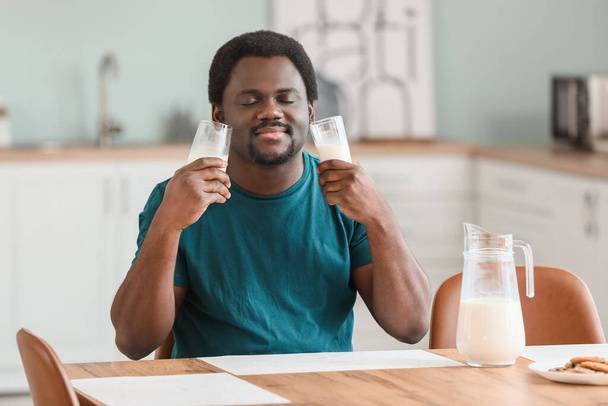 Молодий афроамериканець з молоком на кухні. - Фото, зображення
