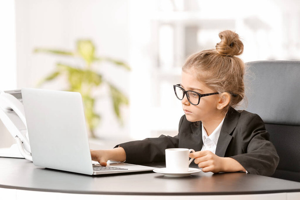 Маленькая деловая женщина с ноутбуком работает в офисе - Фото, изображение