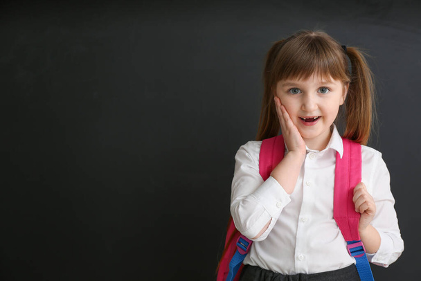 Surprised little schoolgirl near blackboard in classroom - Foto, Imagen