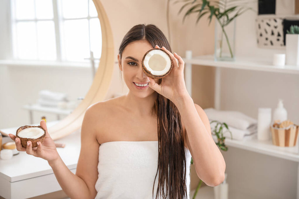 Beautiful young woman with coconut in bathroom - Photo, image