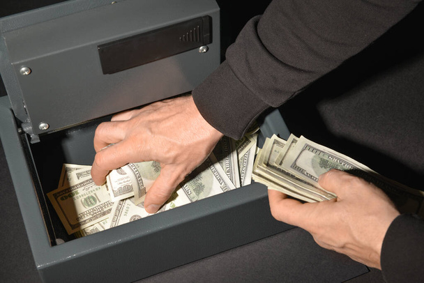 Inbreker steelt geld uit kluis, close-up - Foto, afbeelding