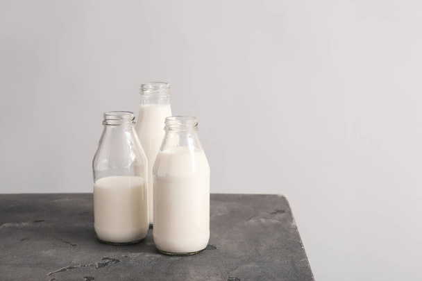 Üvegáruk friss tejjel az asztalon szürke alapon - Fotó, kép