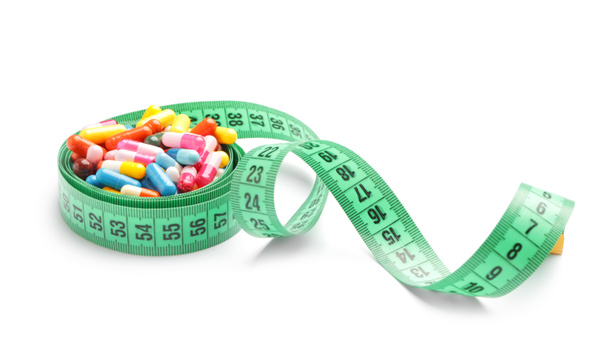 Píldoras de pérdida de peso con cinta métrica sobre fondo blanco
 - Foto, imagen