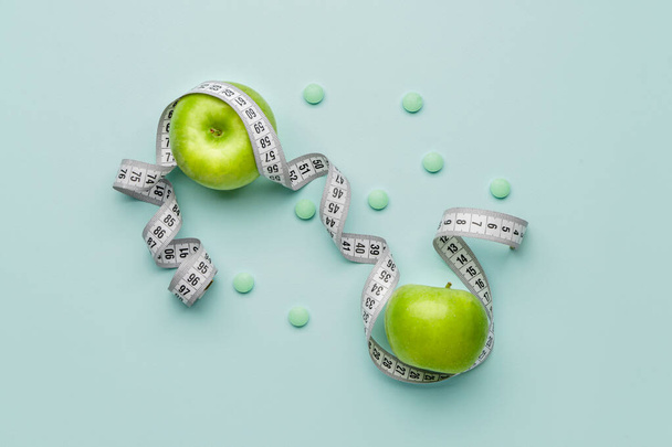 Weight loss pills and measuring tape and apples on color background - Foto, Bild