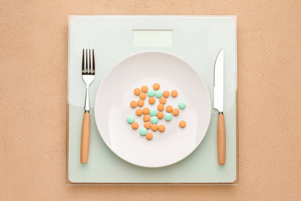 Plate with weight loss pills and scales on color background - Fotografie, Obrázek