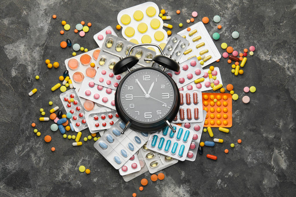 Alarm clock with different pills on dark background - Foto, imagen