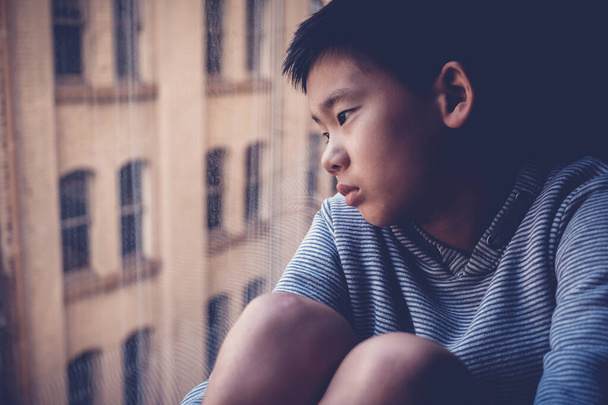 Triste asiático preadolescente sentirse solo, mirando por la ventana de su habitación, distanciamiento social, aislamiento, concepto de salud mental
 - Foto, Imagen