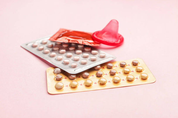 Протизаплідні таблетки та презервативи на кольоровому фоні
 - Фото, зображення