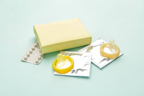 避妊薬と色の背景のコンドーム - 写真・画像