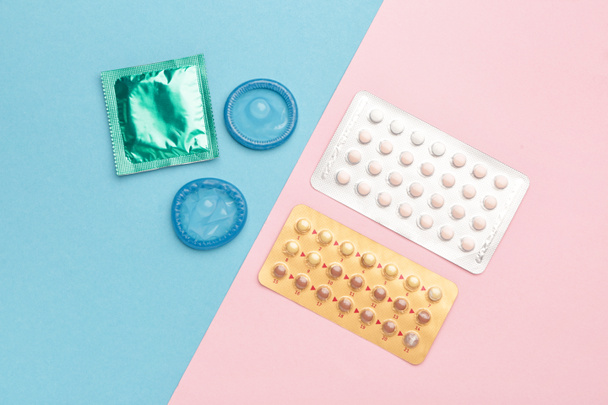 Contraceptive pills and condoms on color background - Photo, Image