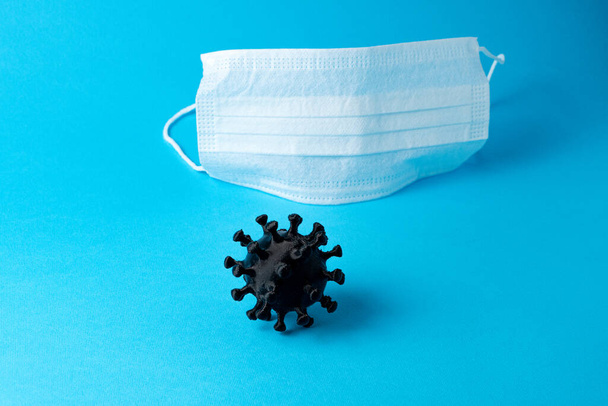 Белая медицинская маска на синем фоне и коронавирус, скопируйте пространство. Пандемия COVID-19
 - Фото, изображение