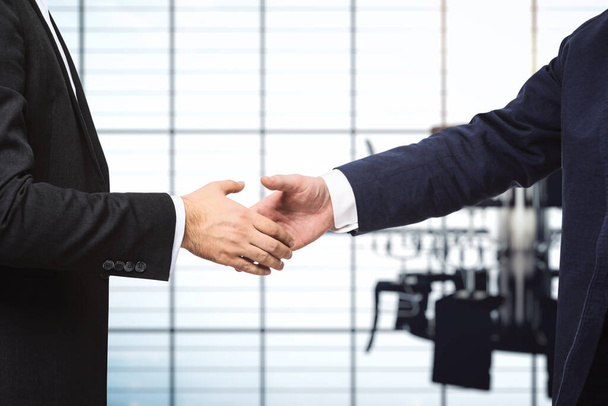 Two businessmen shake hands on the background of sunny conference room, deal concept, close up - Foto, imagen
