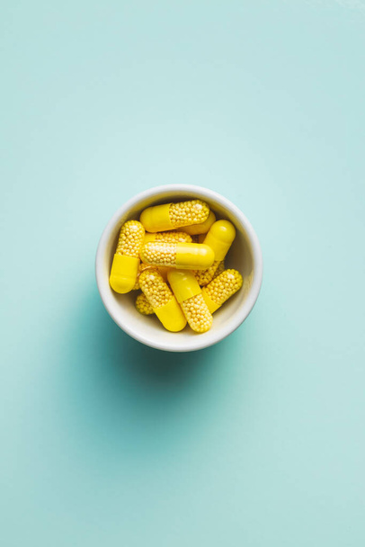 Vitamin capsules. Vitamin C pills in bowl on colorful background. Top view. - Foto, afbeelding