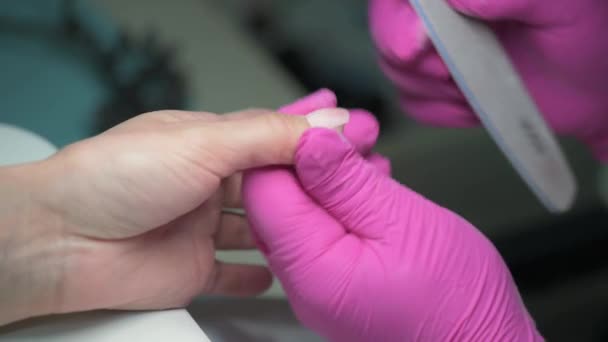 Primer plano del esteticista manicura prepara las uñas de los clientes con una lima de uñas antes de cubrirlo con esmalte
 - Metraje, vídeo
