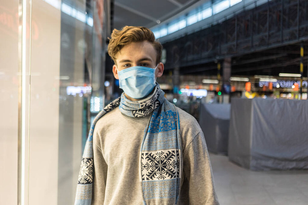 Nuori mies käyttää kertakäyttöisiä lääketieteellisiä naamioita ostoksilla supermarketissa sepelvaltimotautiepidemian aikana. Suojelu ja ehkäisy epidemian aikana. Covid-19 henkilö
 - Valokuva, kuva
