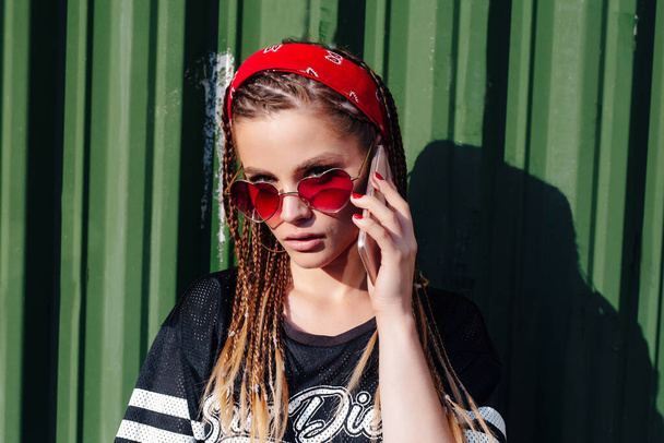 young hipster woman with bandana and braids talking on the phonesmart on sunny summer day outdoor - Fotó, kép