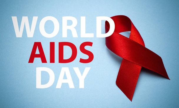 Ruban SIDA sur fond bleu avec texte. Ruban rouge, symbole de la Journée mondiale du sida ou du Mois de la sensibilisation au VIH et concept de soins de santé
. - Photo, image