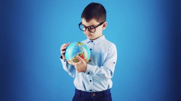 happy funny kid with globe on a blue background. - Felvétel, videó