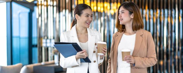 Banner, pagina web o modello di copertina di due imprenditrici asiatiche che parlano durante la pausa caffè in un ufficio moderno o in uno spazio di coworking, pausa caffè, relax e conversazione, concetto di partnership tra imprese e persone
 - Foto, immagini