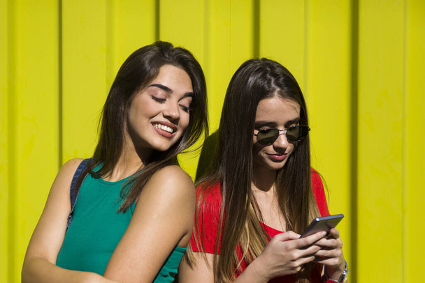 Mujeres jóvenes con cara feliz contra la pared verde escuchar música en los auriculares y divertirse
 - Foto, Imagen