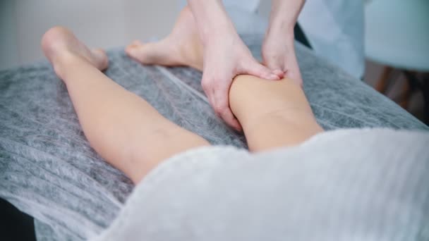 Massage - massage therapist is kneading the legs of her client with thumbs - Footage, Video