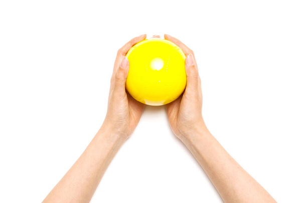 Nainen käsi pitää keltainen pallo eristetty valkoinen
. - Valokuva, kuva