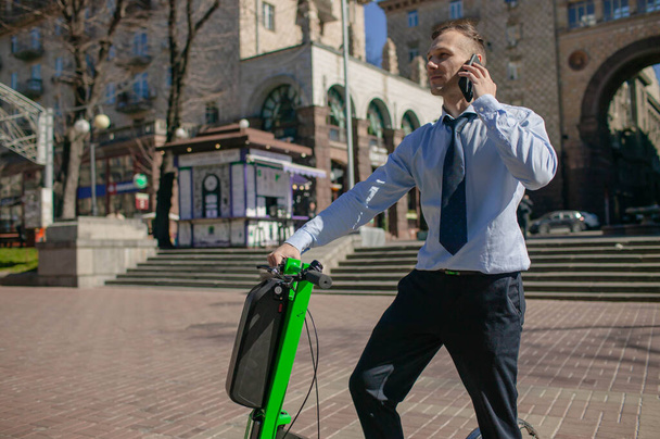 Uomo d'affari con smartphone, zaino e scooter
 - Foto, immagini
