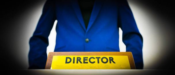 Důvěryhodný obchodník - Ředitel v modré bundě stojí vedle poziční tabulky na stole s názvem - Ředitel. Koncepce hierarchie a řízení podnikání. - Fotografie, Obrázek