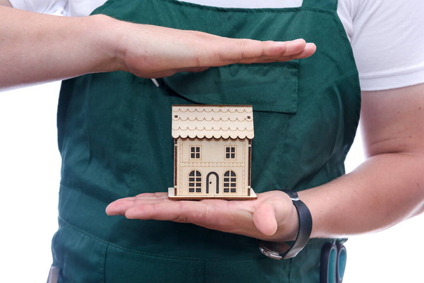Мужчина держит деревянную модель дома на ладони
  - Фото, изображение