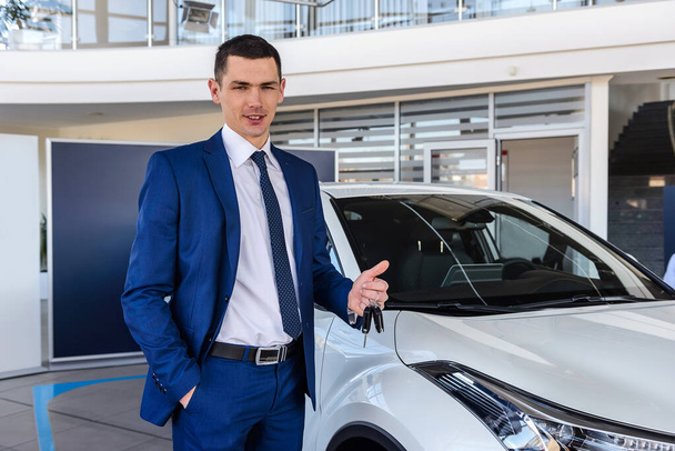 Man in showroom holding keys from new car - Photo, Image