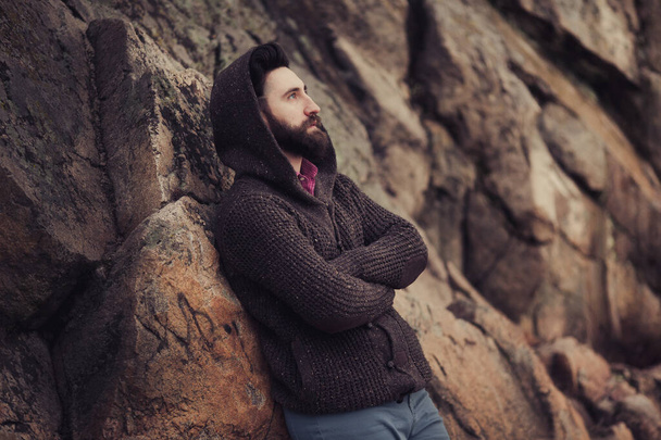 Fiatal szakállas férfi portré. Szomorú, elegáns metroszexuális férfi pózol egyedül a szabadban kötött pulóvert visel. - Fotó, kép
